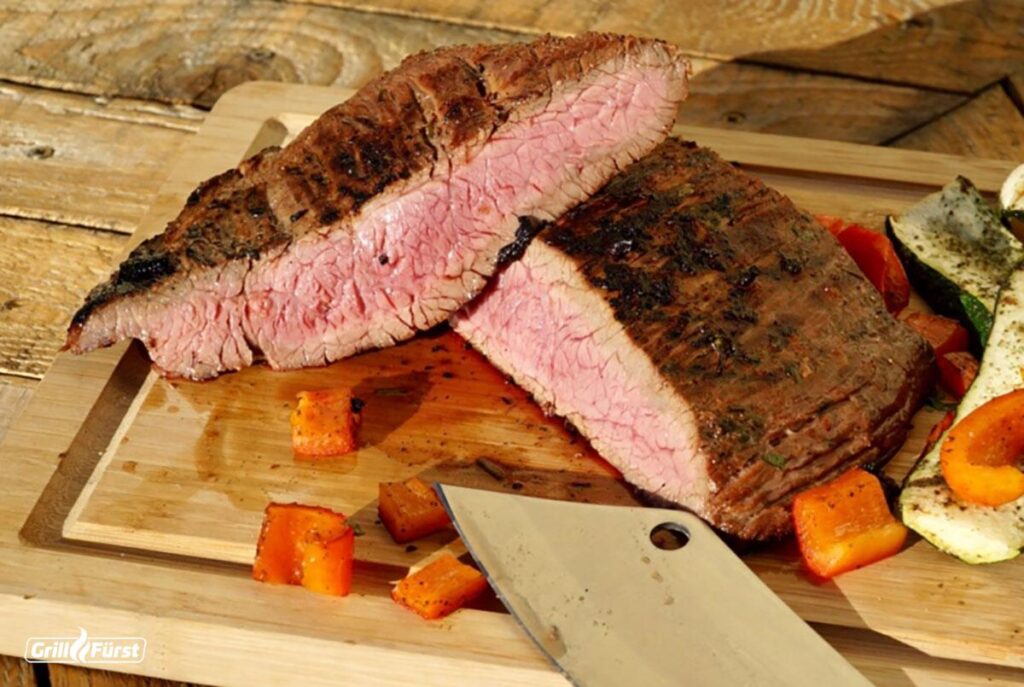 Kerntemperatur Flank Steak: Medium gegrilltes Flanksteak auf einem Holzbrett mit Gemüse