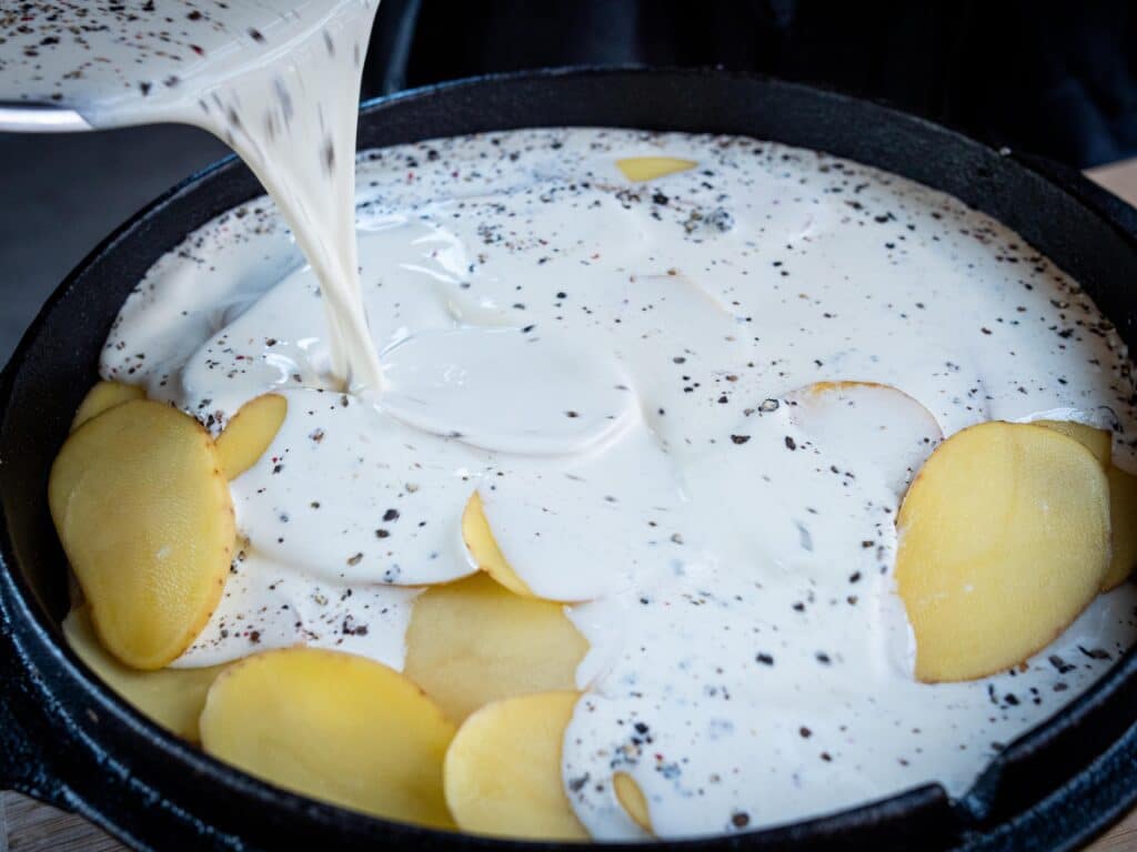 Kartoffelgratin mit Sauce im Dutch Oven übergießen