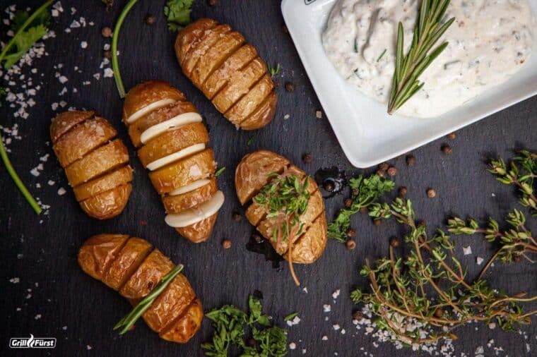 Fächerkartoffeln und Kräuterquark angerichtet auf einer Schieferplatte als vegetarische Hauptspeise
