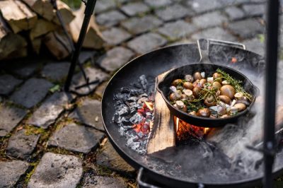 Kochen an der Feuerstelle: Pilze in der Gusspfanne über dem Holzfeuer zubereiten