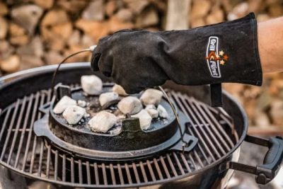 Heiße Grillbriketts mit Grillhandschuhen sicher auf dem Dutch Oven verteilen Heiße Grillbriketts mit Grillhandschuhen sicher auf dem Dutch Oven verteilen